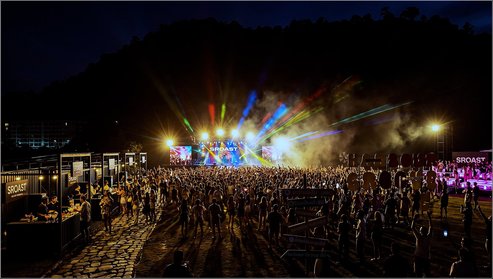 Aerial view of a show night — GA floor, bar line and the lit VIP platform under the hillside.