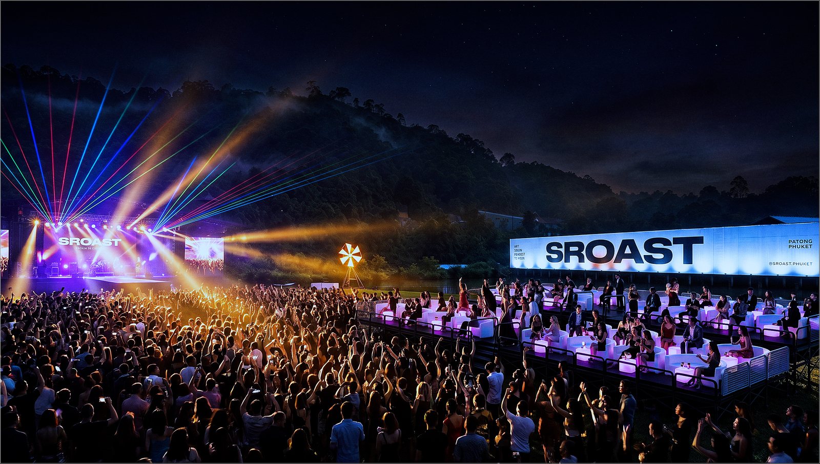 Show night on the VIP platform — guests at glowing lounge tables above the crowd, lasers over the stage.